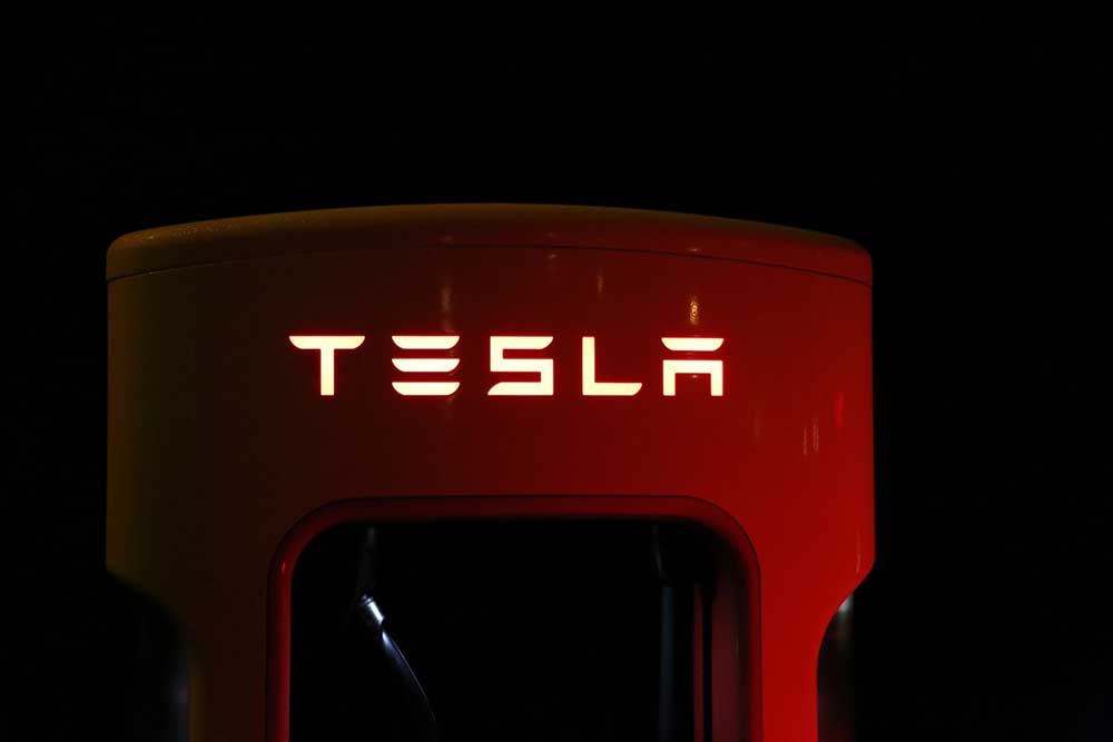 Tesla Supercharger station at night, illuminated with red lighting.