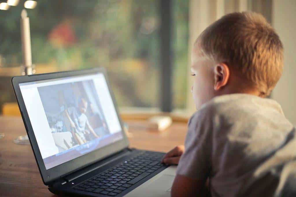 Child using a laptop for video call with friends or family.