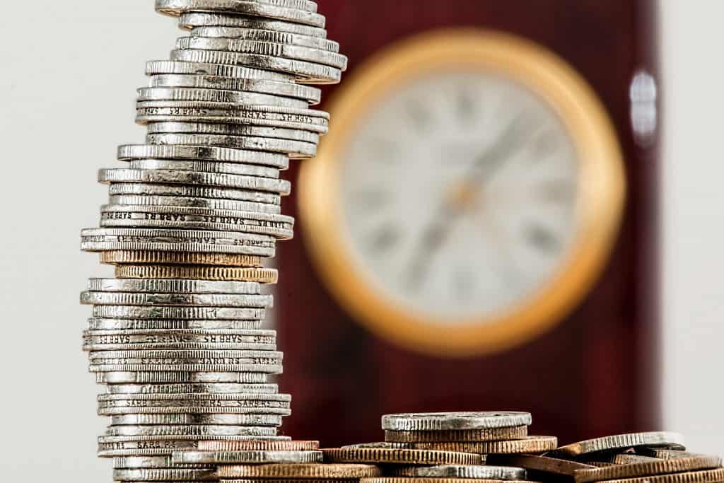 Coins stacked with a blurred clock in the background symbolising economic uncertainty.