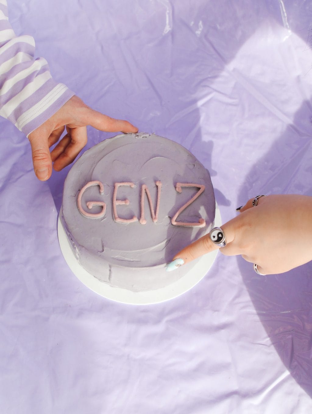 Two hands pointing at a cake with "GEN Z" written on it, symbolising generational differences.