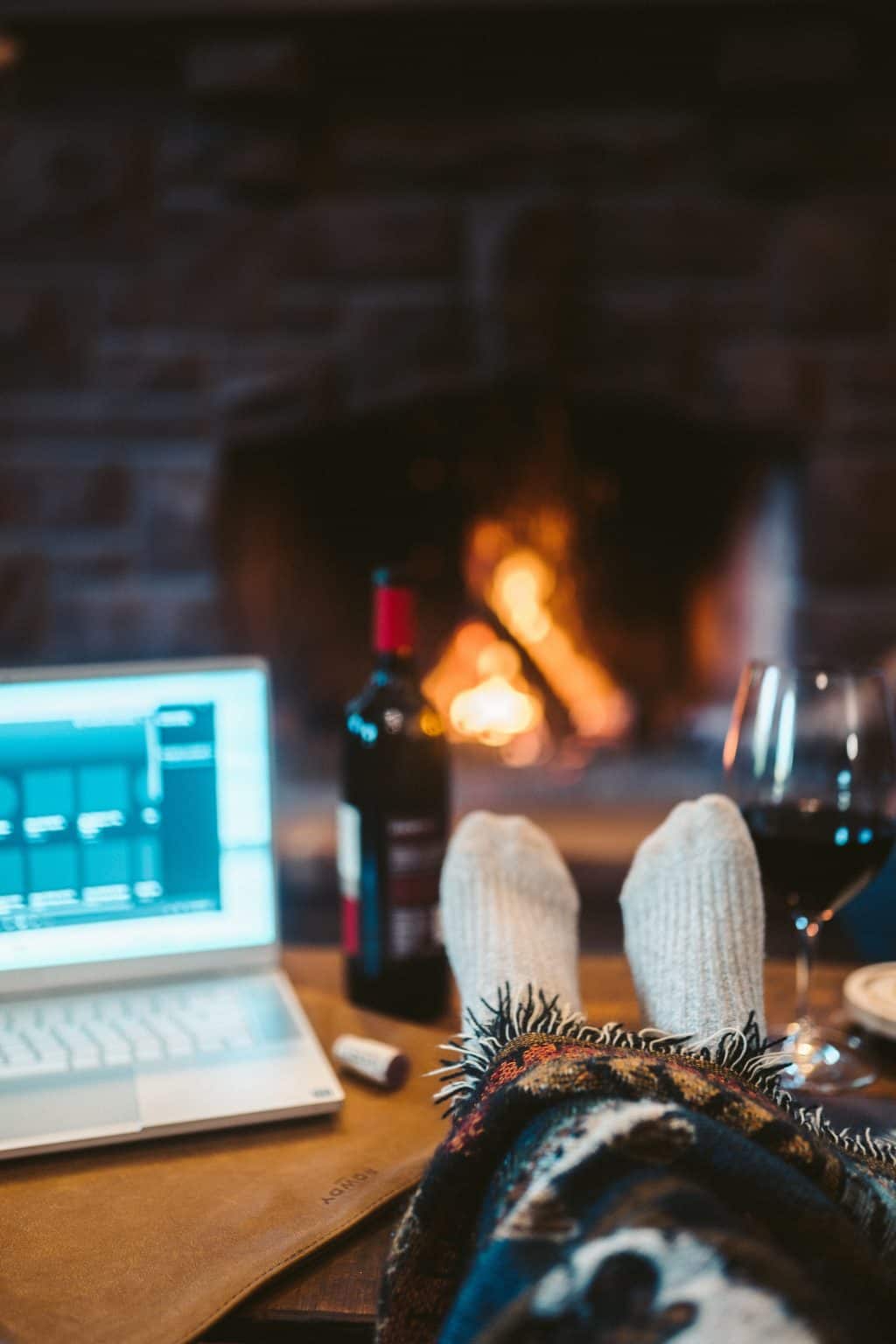 Festive home office with laptop, wine, and fireplace for holiday relaxation.