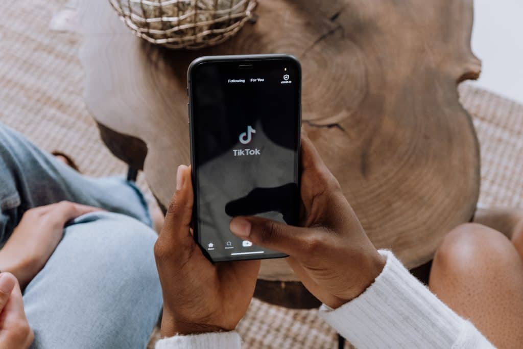 Person holding a smartphone displaying the TikTok app logo.