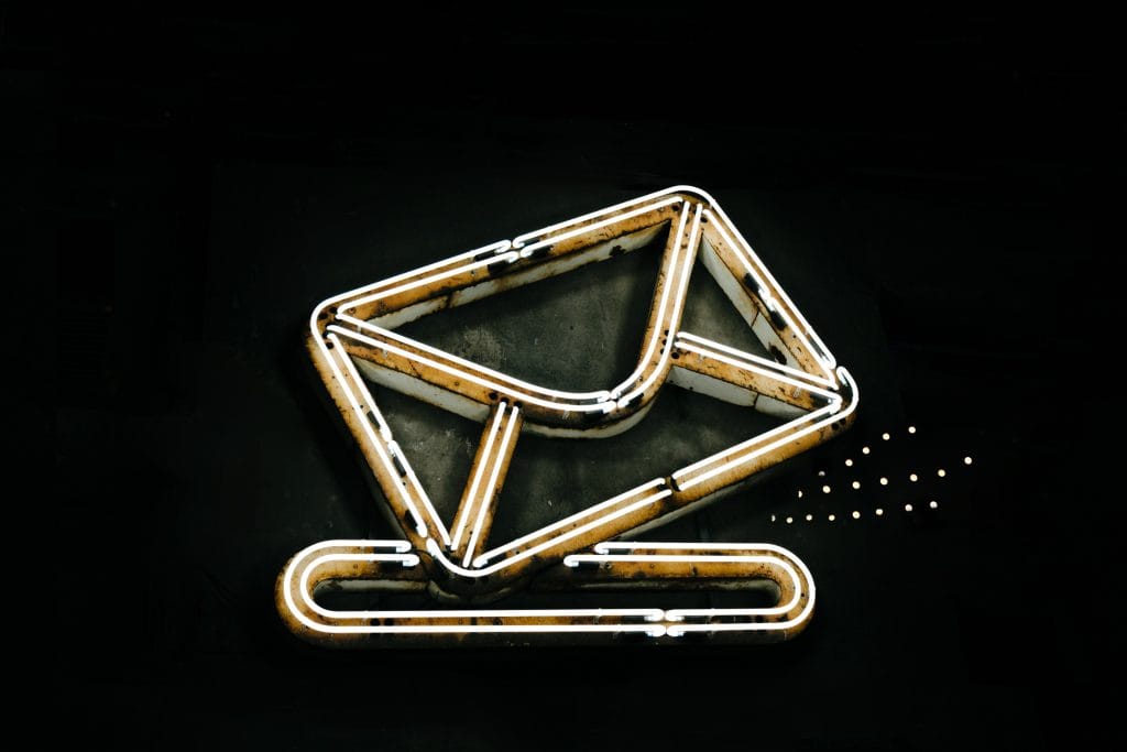 Neon email icon on black background for marketing communication.