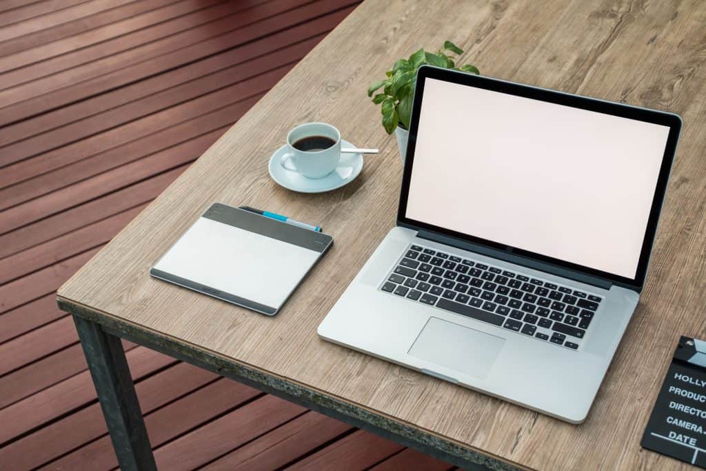 Modern workspace with laptop, notebook, coffee, and plant for CRM management.