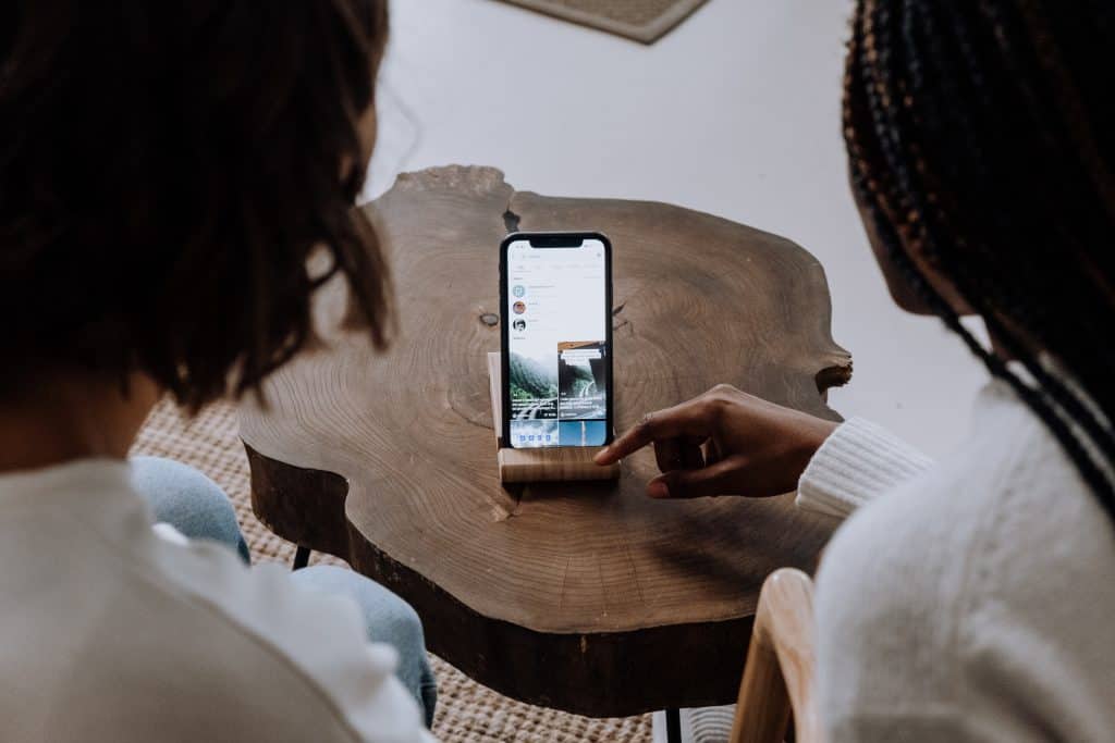 Two women reviewing TikTok ad content on a smartphone at a wooden table.