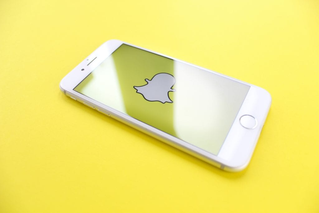 Smartphone displaying Snapchat logo on yellow background.