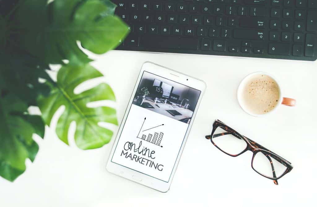 Digital marketing strategy with smartphone, glasses, and coffee on desk.