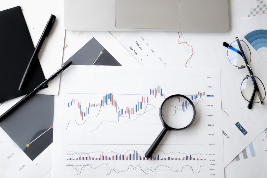Business analytics with charts, magnifying glass, and glasses on data reports.