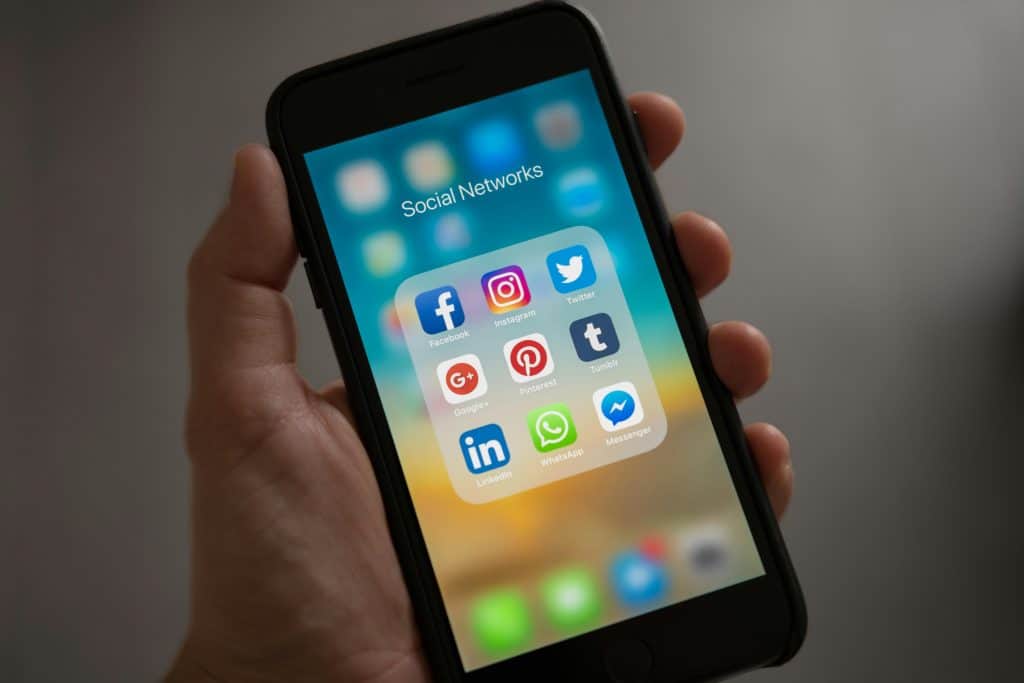 Smartphone displaying social media app icons including Facebook, Instagram, Twitter, and LinkedIn.